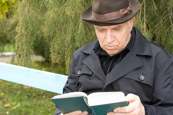 Portrait of an elderly man reading outdoors — Stock Photo, Image