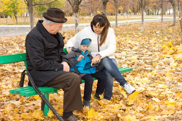 Grandfather, mother and little boy on a park bench — Stock Photo, Image