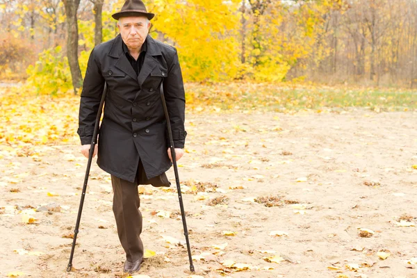 One-legged man walking with crutches in the park — Stock Photo, Image