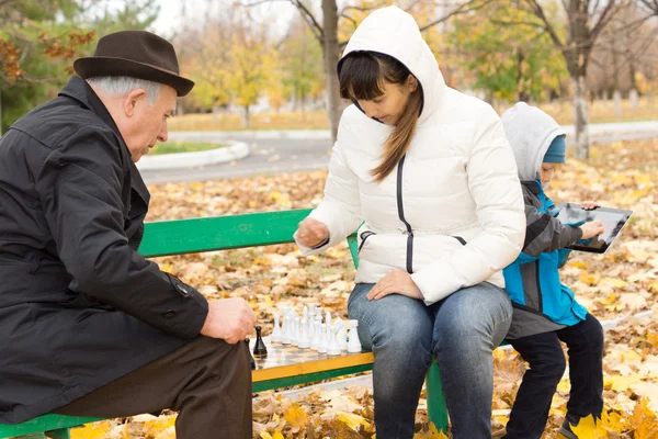 Donna attraente giocare a scacchi con un uomo anziano — Foto Stock