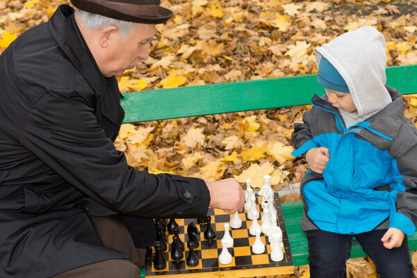 Little boy playing chess with his Grandpa