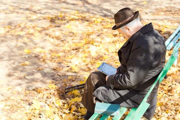 公園での高齢者 1 つ脚男座って読書 — ストック写真