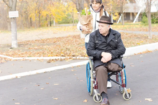 Hombre discapacitado mayor siendo ayudado con sus compras — Foto de Stock