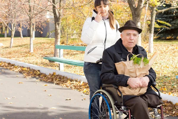 Женщина помогает пожилому инвалиду — стоковое фото