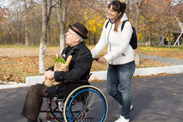 Mujer feliz ayudando a un anciano discapacitado — Foto de Stock