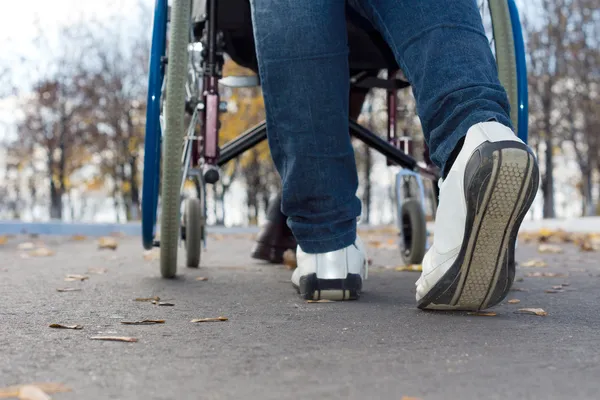 Piedi di una persona che spinge una sedia a rotelle — Foto Stock