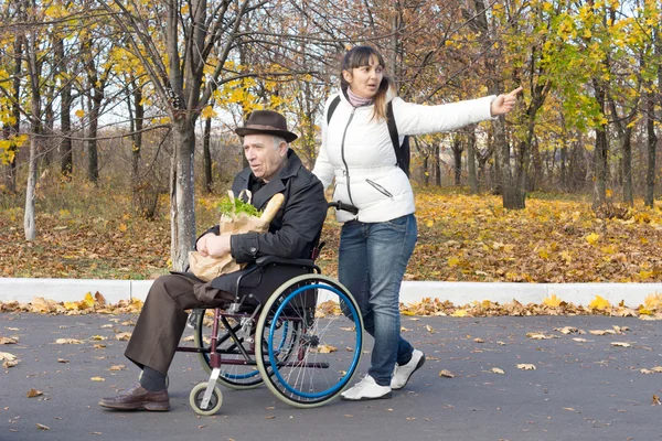 Kadın yaşlı bir adam tekerlekli sandalyede bastırıyor — Stok fotoğraf