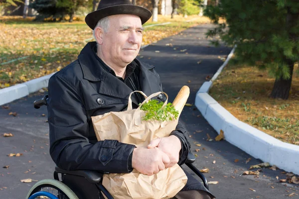 Hombre sonriente en una silla de ruedas con sus comestibles —  Fotos de Stock