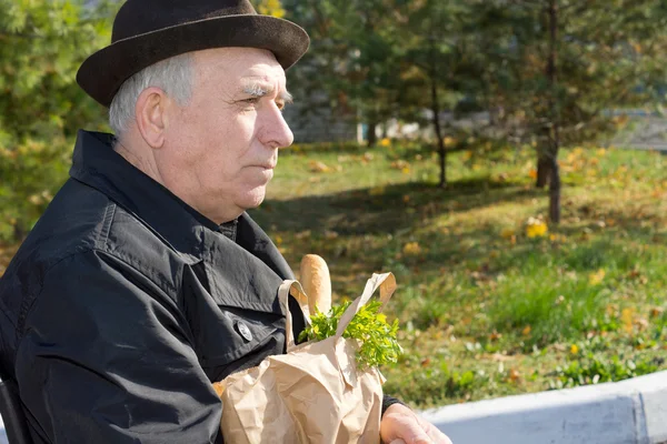 Anciano pensativo hombre con una bolsa de comestibles —  Fotos de Stock