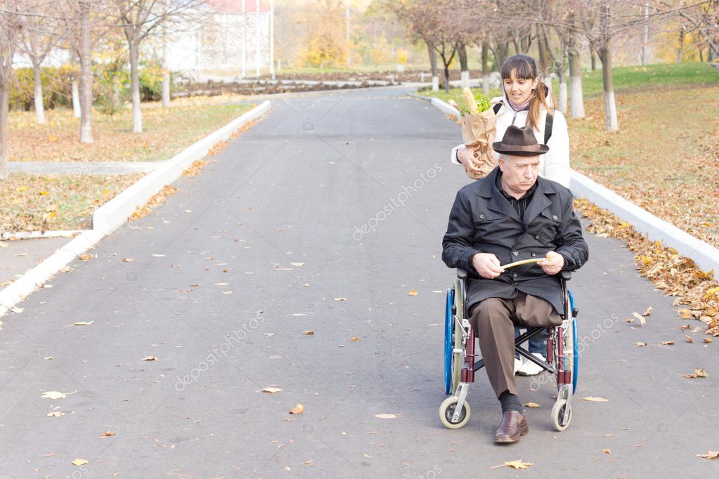 Carer helping a disabled man in a wheelchair — Stock Photo © Vaicheslav
