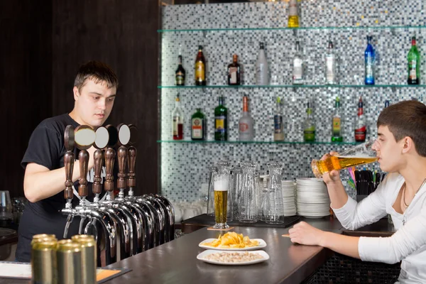 Barman travaillant pendant qu'un client boit au pub — Photo