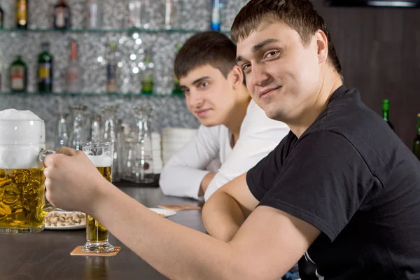 Vriendelijke jonge man bier drinken aan de bar — Stockfoto