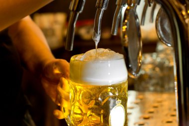 Man pouring a tankard of frothy beer