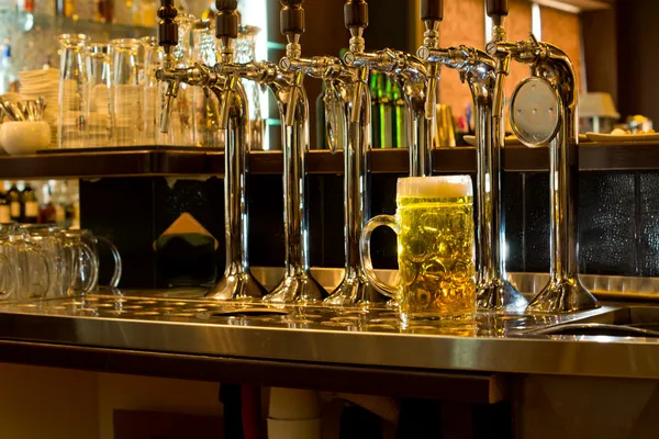 Reihe von Bierzapfstellen in einer Kneipe mit einem Fass Bier — Stockfoto