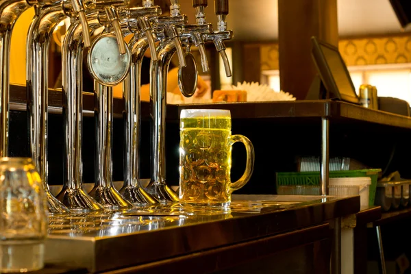 Fila de torneiras anexadas a barris de cerveja de metal em um bar — Fotografia de Stock