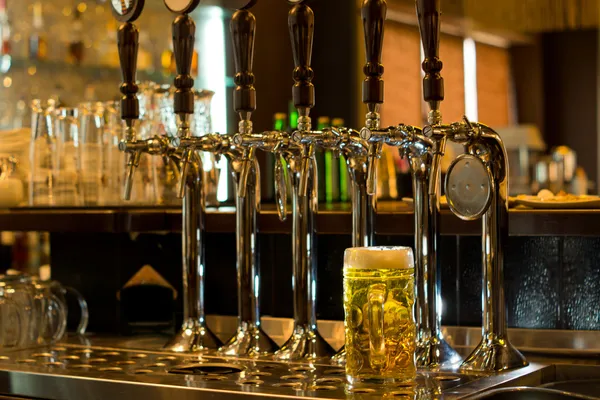 Tankard of beer with beer taps in a pub Royalty Free Stock Photos
