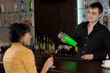 Barmen bir kadınla sohbet ederken bir martini karıştırma