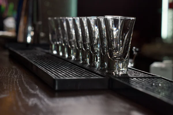 Clean empty shot glasses aligned on the bar — Stock Photo, Image