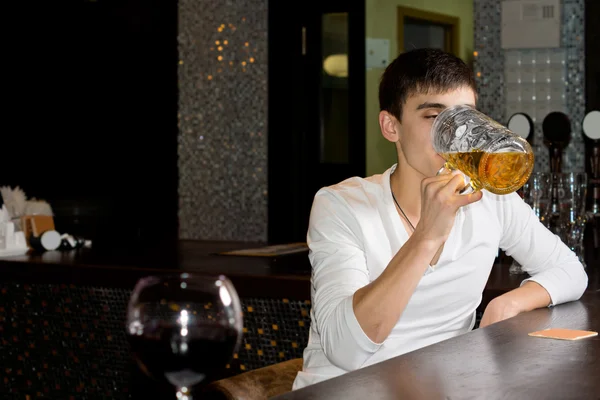 Junger Mann schießt einen großen Krug Bier ab — Stockfoto