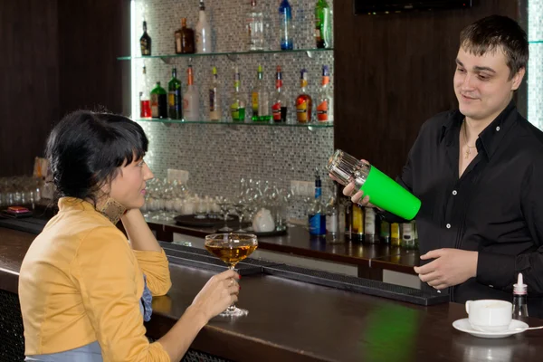 Barman mixing a cocktail for a female customer — Stock Photo, Image