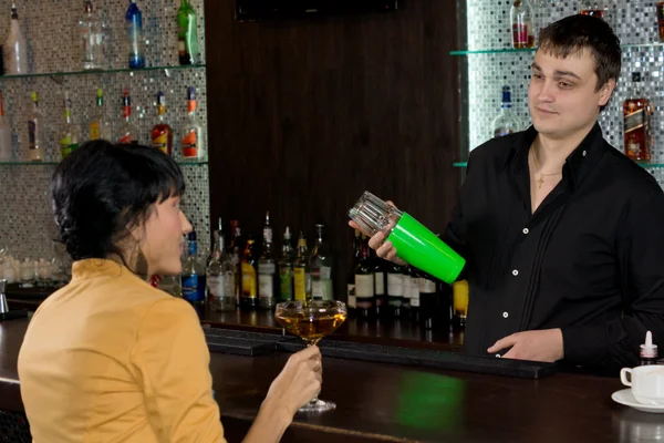 Barman mischia un martini mentre chiacchiera con una donna — Foto Stock