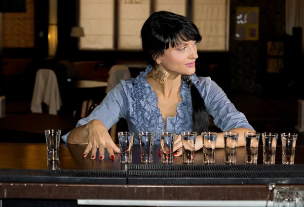 Woman with a row of vodka shot glasses — Stock Photo, Image