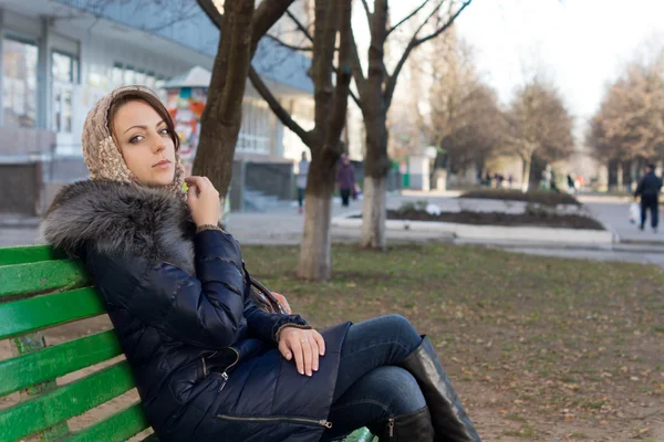 Žena sedí na lavičce v městském parku — Stock fotografie