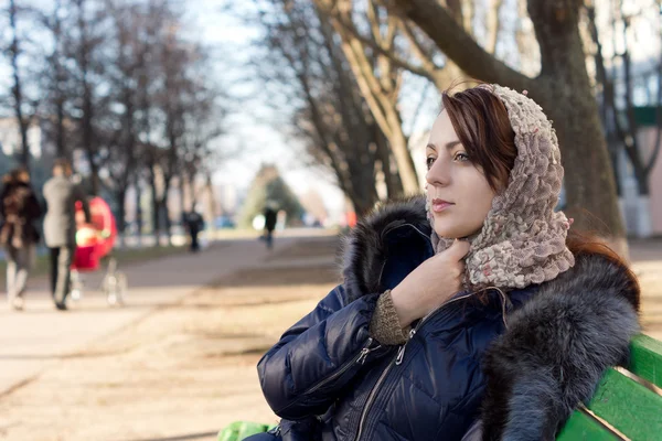 Osamělý mladá žena sedící na lavičce v parku — Stock fotografie