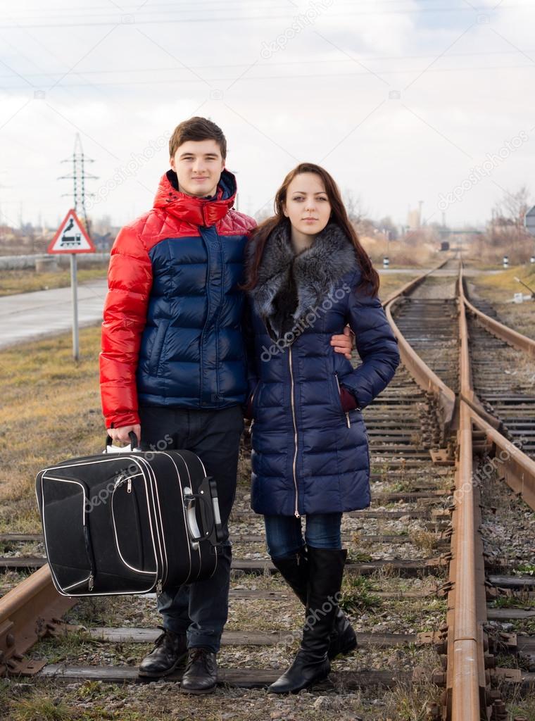 Young couple standing arm in arm with luggage