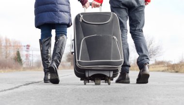 Low angle view of a couple pulling a suitcase clipart