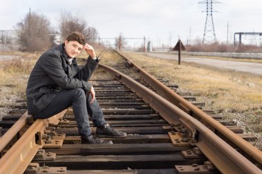 tren yolu metal parça üzerinde oturan genç adam