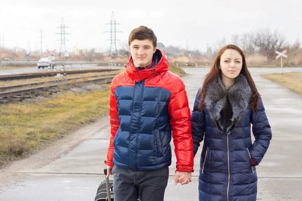 Romántica pareja joven llevando una maleta —  Fotos de Stock