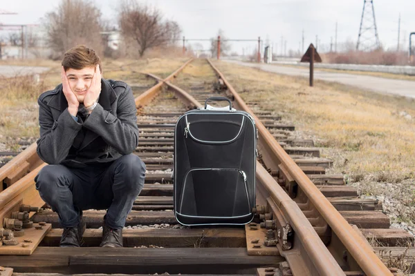 Verveeld jongeman te wachten voor een vertraagde trein — Stockfoto