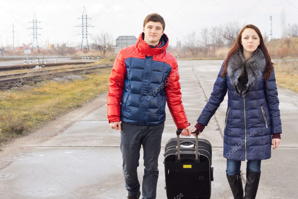 Young man and woman pulling along a suitcase