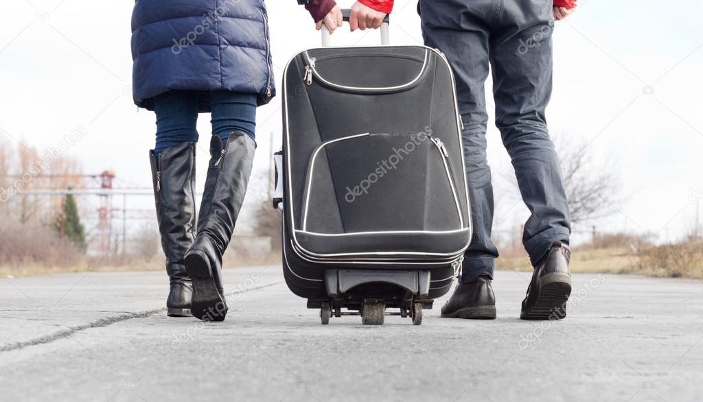Low angle view of a couple pulling a suitcase