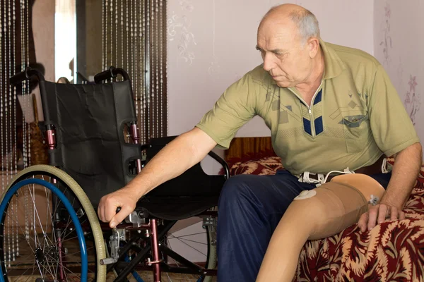 Uomo anziano con gamba artificiale e sedia a rotelle — Foto Stock