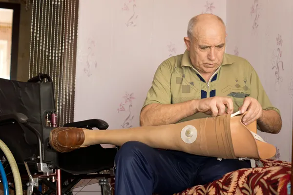 Hombre mayor revisando su pierna protésica — Foto de Stock