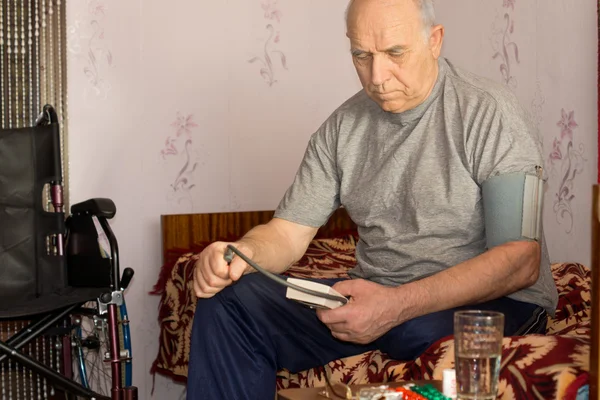 Homem com deficiência sênior tomando sua própria pressão arterial — Fotografia de Stock