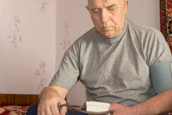 Elderly man taking his blood pressure — Stock Photo, Image