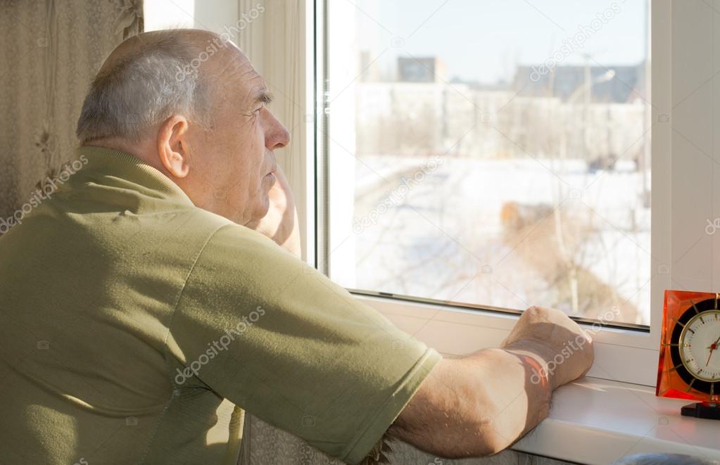 Senior man standing reminiscing at a window