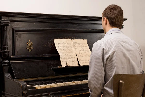 Genç adam bir piyano üzerinde notalar — Stok fotoğraf