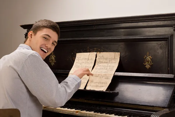 Jovem rindo enquanto se senta tocando piano — Fotografia de Stock