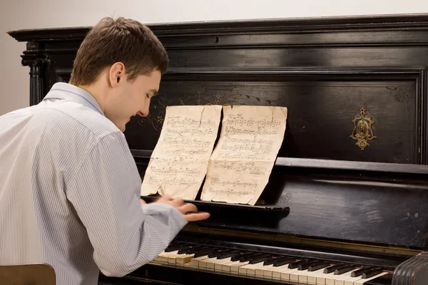 Junger Mann lächelt, während er Klavier spielt — Stockfoto