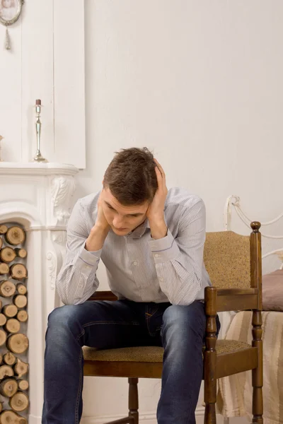 Mladý muž sedící myšlení v obývacím pokoji — Stock fotografie