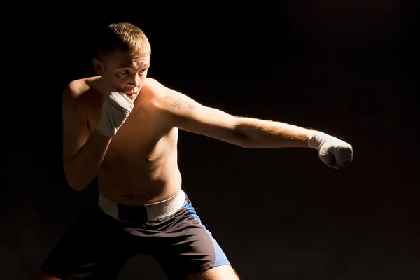 Pugnacious joven boxeador lanzando un golpe — Foto de Stock