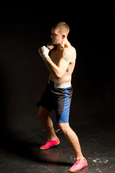 Retrato oscuro de un joven boxeador en forma en el ring — Foto de Stock