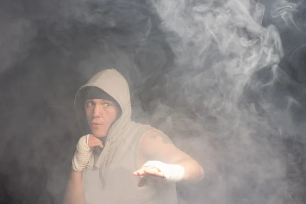 Joven boxeador luchando en una habitación oscura y ahumada —  Fotos de Stock