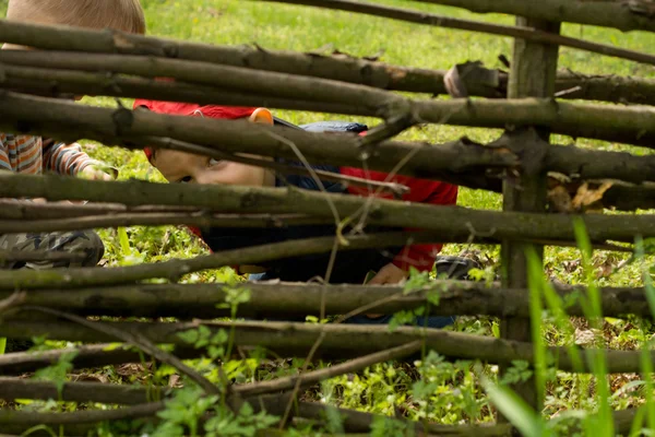 Nieuwsgierige kleine jongen "peering" door een hek — Stockfoto