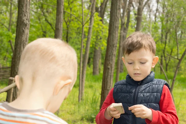 Serious little boy standing lighting a match — Stock Photo, Image