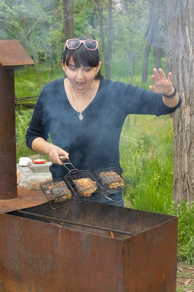 Mulher cozinhar em um churrasco chamando — Fotografia de Stock